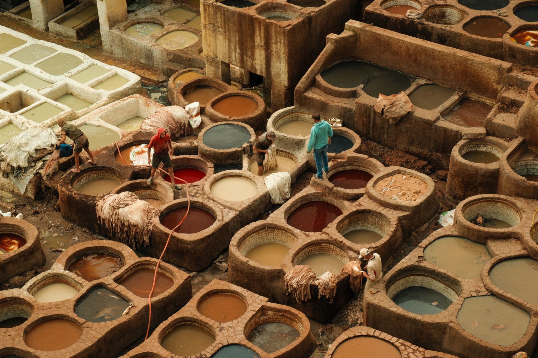 Workers at the Chouara leather tanneries in the Fes medina, Morocco, with colorful dye pits
